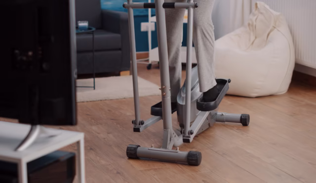 Old person riding stationary bicycle and exercising at home